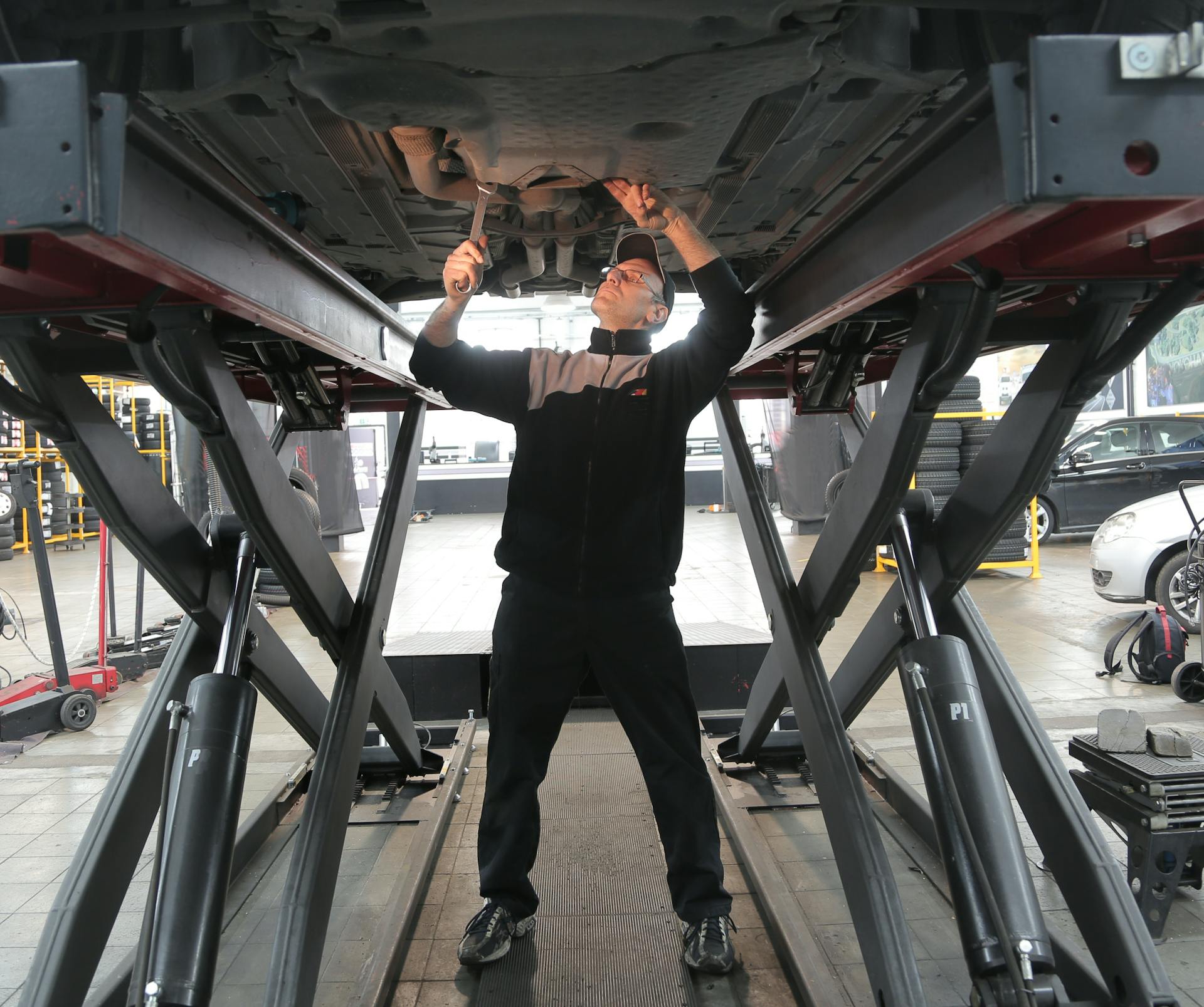 Mechanic inspecting vehicle undercarriage during diagnostic service