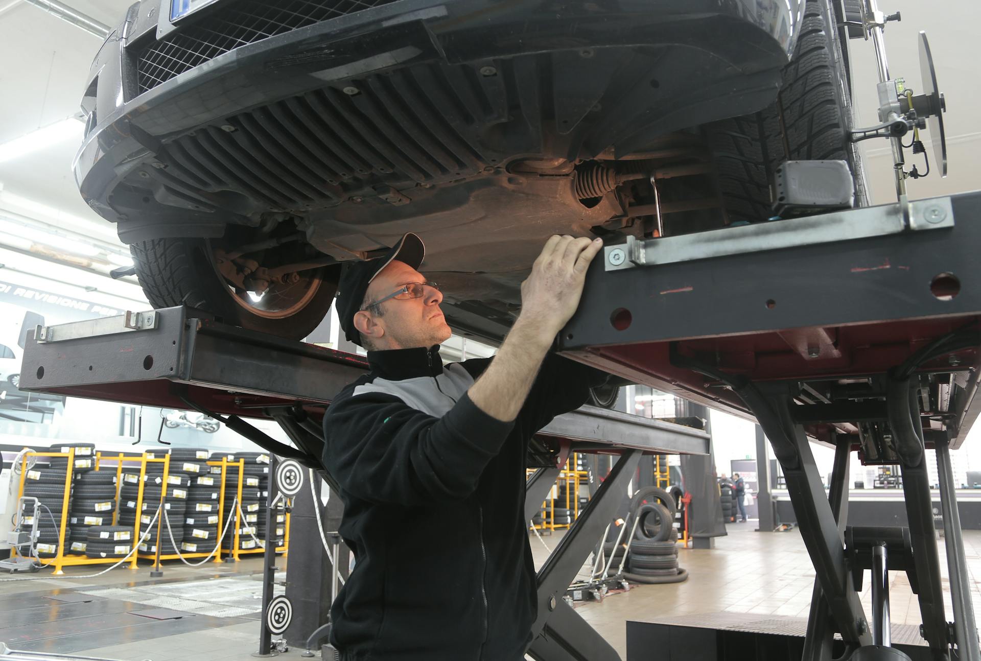 Mechanic inspecting vehicle suspension and steering components on lift at Pro Automotive Repair in Sachse TX